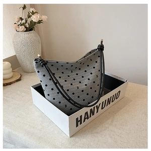Detailed view of gray polka dot tote bag with black rope handles in a stylish setting