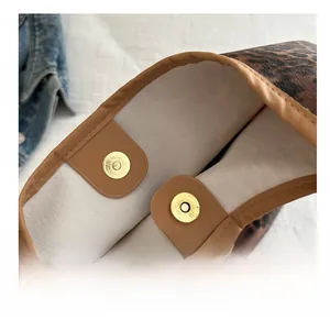 Gros plan sur la boucle magnétique dorée et la doublure beige du sac cabas léopard