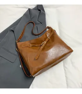 Dettaglio della borsa tote vintage marrone con fibbia dorata su sfondo blazer grigio