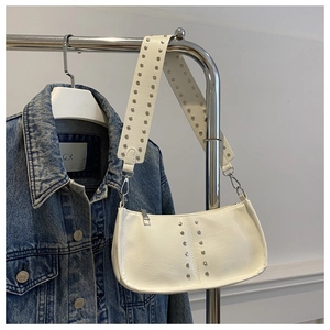 Détail du sac à bandoulière en cuir blanc avec des rivets argentés et une large sangle