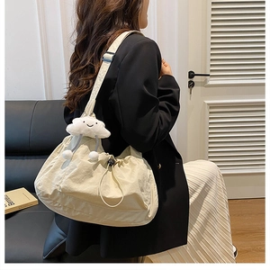Detail of beige nylon crossbody bag featuring drawstring design and cute plush charm