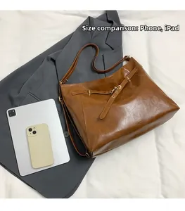 Vista macro della grande borsa tote in pelle marrone con telefono e tablet per misura