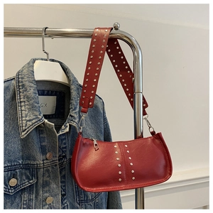 Détail macro du sac à bandoulière rouge avec rivets ronds argentés et zip en métal
