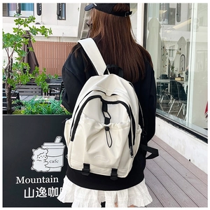 Rear view of a white nylon school backpack with black accents on a female model