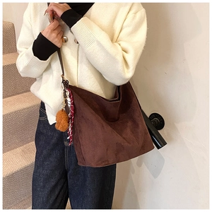 Brown suede tote bag with plush bear charm and plaid scarf detail on model