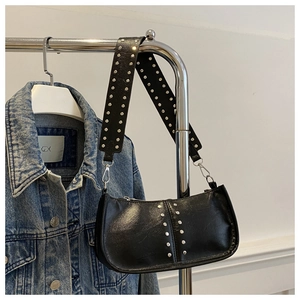 Détail d'un sac à bandoulière punk noir avec clous argentés sur une veste en jean