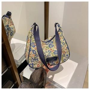 Detail of floral tapestry fabric and navy blue canvas strap on crescent handbag