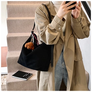 Minimalist black canvas tote bag with a cute brown poodle plush pendant in a casual street view