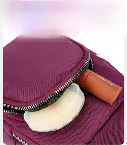 Detail view of burgundy nylon phone bag front zipper pocket with lipstick and powder