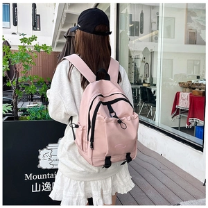Pink nylon school backpack shown in a lifestyle outdoor setting with model back view