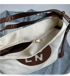 Detailed close-up of canvas tote zipper closure and premium brown leather LN logo badge