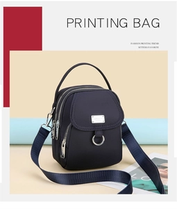 Detail view of navy blue nylon crossbody bag featuring three zipper pockets and wide strap