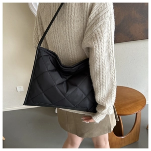 Detail of black quilted oxford cloth tote bag showing classic rhombus pattern and shoulder strap