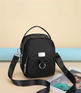 Close-up of lightweight black crossbody bag with multiple zippers and metal logo plate
