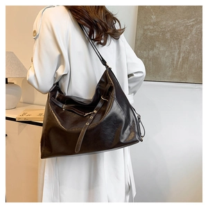 Vista laterale di una grande borsa tote vintage in pelle cerata marrone indossata da una modella