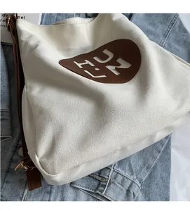 Detailed close-up of heart leather patch and HULN cutout on off-white canvas tote bag