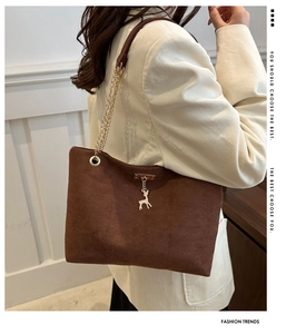 Détail du sac cabas en daim marron avec pendentif cerf argenté et bandoulière chaîne