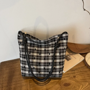 Polka dot canvas tote bag with black bow embroidery and slim leather handles on a desk