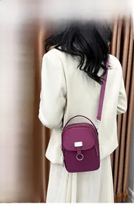 Vertical deep purple nylon crossbody phone bag shown on a model with adjustable strap