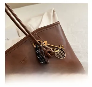 Dettaglio di una borsa tote vintage marrone scuro con ciondolo a racchetta da tennis