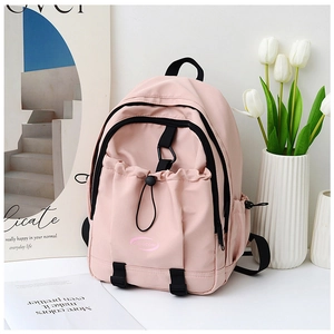 Pink nylon backpack detail showing the embroidered brand logo and drawstring front pocket