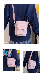 Detail of pink canvas crossbody bag showing front pocket and adjustable fabric strap