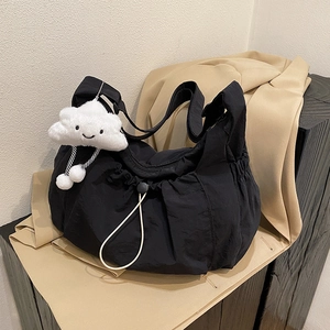 Minimalist black nylon tote bag with cute white cloud pendant on a beige blazer