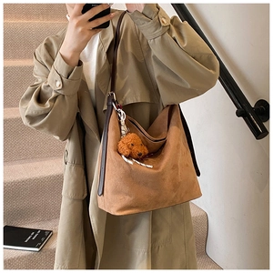 Detail of soft brown suede tote bag featuring a cute teddy bear plush charm on the side