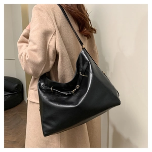 Vista laterale di una modella che indossa una grande borsa hobo in pelle nera con tracolla