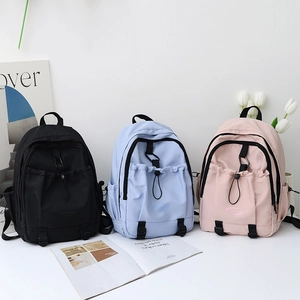 Detailed view of nylon backpacks in black, light blue, and pink with drawstring pockets