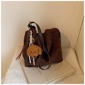 Detail of soft brown faux suede tote bag with cute teddy dog plush charm on a book