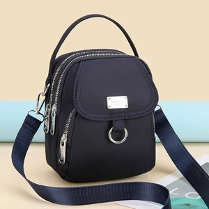 Macro view of compact navy blue nylon phone bag with triple zippers and silver metal logo