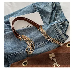 Gros plan du sac en daim marron avec poignée en chaîne dorée et pendentif cerf