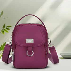 Detail view of deep purple nylon multi-zipper phone bag with adjustable shoulder strap