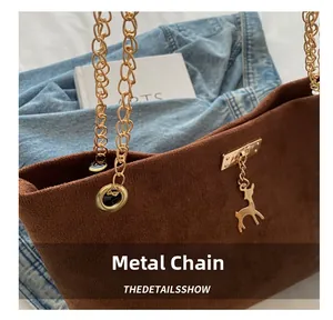 Détail du sac cabas en daim marron avec chaînes dorées et pendentif cerf élégant
