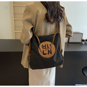Detail of black canvas tote bag with brown leather patch and shoulder straps for daily commute