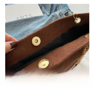 Détail du fermoir magnétique doré sur un sac bandoulière vintage en daim marron avec chaîne