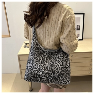Détail d'un grand sac cabas à motif léopard porté à l'épaule sur un pull beige