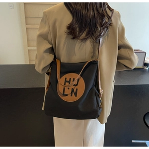 Detail of canvas tote bag showing the brown leather logo patch and shoulder strap design