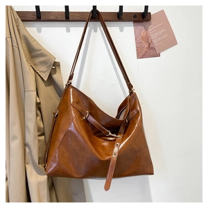 Dettaglio della borsa tote in pelle cerata caramello con fibbia metallica e tracolla lunga