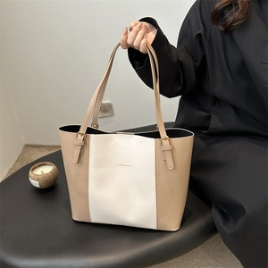 Detail of beige and white tote bag with gold metal buckle and leather straps