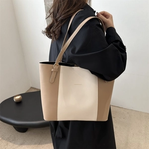 Detailed close-up of beige tote bag with gold metal buckle and fashion text