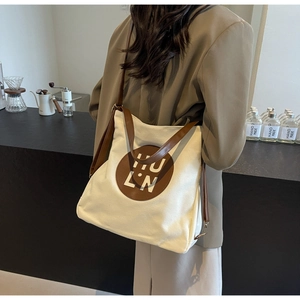 Detailed view of cream canvas tote bag with brown leather HULN logo patch