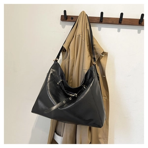 Dettaglio della borsa hobo in pelle nera con tracolla regolabile su un gancio a muro