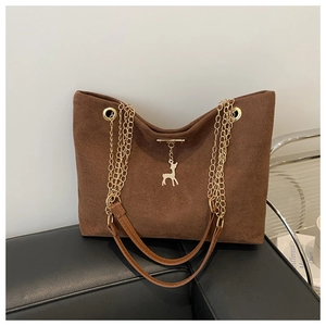 Détail du sac cabas en daim marron avec bandoulière dorée et pendentif cerf chic