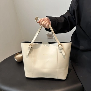 Close-up of off-white leather tote bag featuring gold hardware and logo branding
