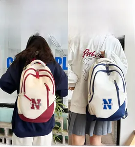 Close-up of dual-color canvas backpack with embroidered N logo and side pocket