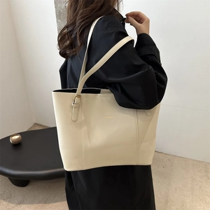 Detailed side view of a cream leather tote bag shown on model for size perspective