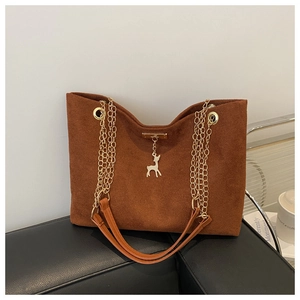 Détail du sac cabas en daim marron avec une bandoulière dorée et un pendentif cerf