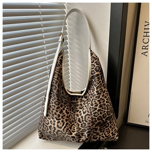 Détail d'un sac cabas léopard avec bandoulière blanche sous une lumière artistique